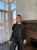 Blusa negra brillante de mangas largas abullonadas.