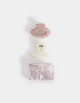 Set de tres broches para el pelo de resina y plástico, con diferentes formas y esmaltados. Incluye un broche ovalado color rosa, un broche con forma de moño color crema y un broche rectangular con estampado carey en tonos lila y blanco.
