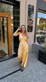 Vestido largo color durazno con escote pronunciado en V y aberturas laterales en la cintura. Presenta un drapeado frontal y falda con tajo lateral.