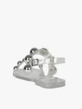 Sandalias bajas negras de PVC con dos tiras horizontales adornadas con apliques esféricos plateados.