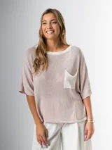 Remera tejida en hilo italiano, color beige, con cuello a la base y bolsillo frontal. De caída relajada y silueta amplia.