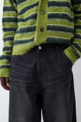 Pantalón de jean negro de corte amplio estilo skater, con tiro medio, cierre de botón y cremallera, y diseño clásico de cinco bolsillos.