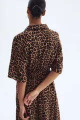 Vestido midi con estampado de leopardo, cuello camisero, manga corta y botonadura frontal. Presenta elástico en la cintura y cinturón extraíble para atar.