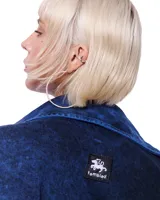Camisa de denim azul, de corte amplio y estilo artesanal, con cierre frontal y detalles en costura.