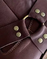 Bota corta de cuero color marrón, con taco de madera y punta cuadrada. Presenta una correa con hebilla alrededor del tobillo.