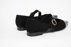 Zapato guillermina de gamuza negra con puntera de charol brillante y tira sobre el empeine con hebilla dorada. Tacón bajo y cuadrado.