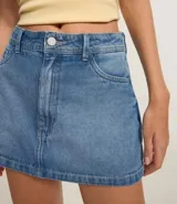 Short pollera de tiro alto confeccionado en denim azul con bolsillos delanteros y traseros. Presenta detalles deshilachados en los bolsillos.