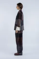 Blazer con estampado a cuadros en tonos marrones y negros, de corte recto y silueta relajada. Presenta solapas clásicas, cierre frontal con botones y bolsillos con tapa. Mangas largas con puños blancos.