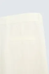 Pantalón color crema de lino, corte relaxed fit, con pliegues frontales, bolsillos laterales y traseros de vivo.