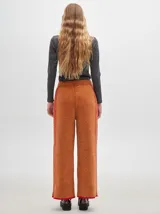 Pantalón ancho color marrón óxido, de textura tipo terciopelo con pespuntes a los lados.