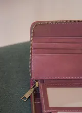 Billetera rectangular de cuero color naranja con cierre de cremallera y diseño geométrico en relieve.