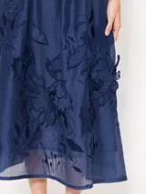 Pollera larga hasta los tobillos, confeccionada en organza color amarillo pálido. Presenta cintura elastizada y flores de tela aplicadas a mano en el delantero.