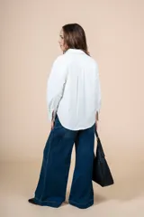 Camisa blanca de corte clásico con bolsillo en el pecho, mangas largas y botones al tono.