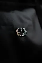 Bolso duffel negro de cuero sintético con logo de ancla bordado en rosa. Tiene doble asa de mano reforzada, correa de hombro regulable y desmontable, cierre superior con doble cremallera y tres bolsillos (dos exteriores y uno interior).