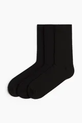 Pack de tres pares de medias de vestir negras, de caña media, confeccionadas en tejido de punto de algodón con textura acanalada y puño elástico.