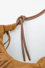 Bolso de hombro tipo hobo color rojo oscuro, confeccionado en material tipo gamuza o nobuk, con flecos largos en la parte inferior. La correa es delgada y se anuda en la parte superior.