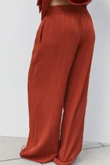 Pantalón marrón de tiro alto con cintura elástica, bolsillos delanteros y pernera ancha.