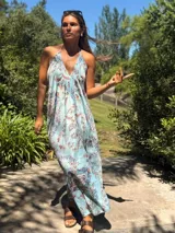 Vestido largo celeste con estampado floral, escote halter y espalda descubierta.