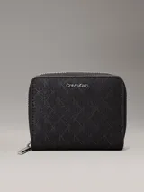 Billetera mediana negra con cierre perimetral y textura de monograma en relieve. Presenta el logo metálico de Calvin Klein en el frente y herrajes plateados.