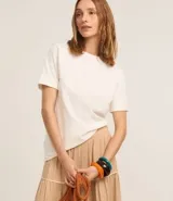 Remera de malla color blanco, de corte recto y mangas cortas con dobladillo.