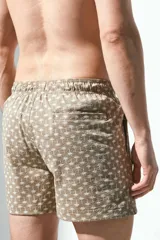 Short de baño color marrón con estampado de palmeras, con cintura elástica ajustable con cordón, bolsillos laterales y trasero con cierre autoadherente.