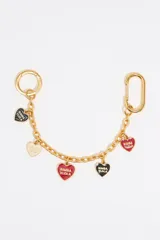 Charm para bolso de cadena de metal dorado con mosquetones en los extremos y dijes colgantes en forma de corazón con el logo de Bimba y Lola en varios colores: negro, rojo y blanco.