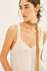 Top bretelero azul oscuro con escote en V, ribetes de puntilla a tono en escote, breteles y sisas. Presenta tachas termo adhesivas distribuidas en el frente.