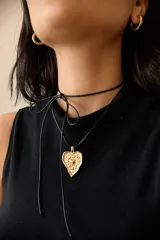 Collar con tiento encerado negro y dije dorado con forma de corazón texturizado.