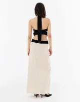 Vestido largo de lino color crudo, con escote halter cruzado en blanco y negro, y calados en los costados.
