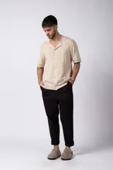 Camisa de tejido de punto color beige, con cuello tipo bowling, manga corta y corte relajado. Cierre frontal con botones.