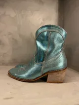 Bota tejana de cuero color celeste metalizado, con bordados en beige y taco de madera.