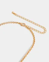 Collar corto dorado con cadena de eslabones y dijes colgantes: moño, zapatos de ballet, corazón y la Torre Eiffel.