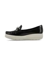 Mocasín de cuero charol negro con plataforma blanca y detalle de hebilla metálica plateada en el empeine.