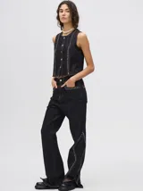 Pantalón de jean azul de tiro alto y corte oxford con apliques metálicos en bolsillos y laterales.