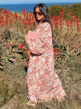 Vestido largo de corte amplio con estampado floral en tonos rosa, marrón y celeste. Tiene escote en V y mangas largas abullonadas.