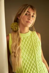 Chaleco marrón de punto con diseño trenzado, cuello redondo y sisas con volantes celestes.