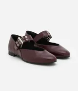 Zapatilla color borgoña de charol sintético, con puntera redonda, tira sobre el empeine con hebilla metálica plateada y taco bajo.