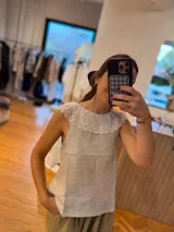 Blusa sin mangas confeccionada en lino color crudo, con cuello babero de tul bordado con flores.