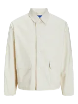 Campera color hueso de corte recto, con cuello clásico, cierre con botones a presión, puños abotonados y bolsillos frontales tipo parche.