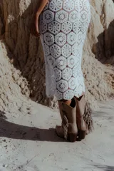 Chaleco largo calado color blanco, tejido al crochet, sin mangas y con caída fluida.