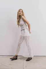 Bota corta de cuero color marrón, con taco cuadrado y punta fina. Presenta una correa con tachas pequeñas y una argolla metálica decorativa alrededor del tobillo. Cuenta con cierre lateral.