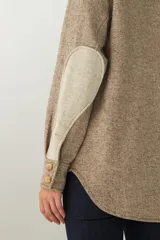 Camisa estilo leñador color beige con textura de espiga, de manga larga con puños abotonados, cuello clásico, cierre frontal con botones y dos bolsillos de parche con solapa abotonada en el pecho.