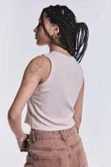 Musculosa beige de punto canalé con cuello redondo y sisa americana. Decorada con tachas y strass plateados.