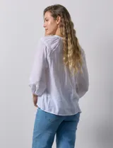 Blusa blanca de gasa bambula con cuello a la base y apertura central con botones. Apliques de crochet en la parte delantera y en las mangas ¾ con terminación fruncida.