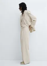 Pantalón de vestir color beige, de corte wide leg, con trabillas, bolsillos laterales, pinzas, tiro medio y cierre oculto de botón, gancho y cremallera.