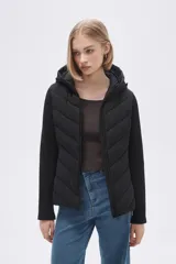 Campera negra con capucha, mangas largas y cierre frontal. Diseño acolchado en el cuerpo y mangas de tejido liso.