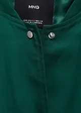 Chaqueta bomber verde esmeralda de lino y lyocell, con cuello redondo, cierre frontal con botones a presión, cintura y puños elásticos, dos bolsillos de parche con solapa en el pecho y corte cropped.