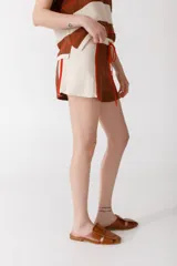 Short tejido en jersey color marrón con detalles de rayas verticales en color crema y ribete naranja.