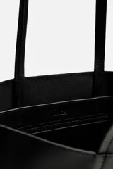 Bolso tipo shopper fabricado en cuero color negro. Tiene un bolsillo interior plano con cierre mediante cremallera y asas de cuero.