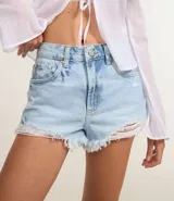 Short de jeans azul claro, modelo slim fit, con roturas y terminación deshilachada en el ruedo. Presenta tiro medio/alto con trabillas para cinturón y cierre frontal tradicional.